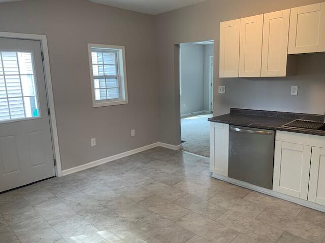 kitchen with dishwasher, white cabinetry, and sink