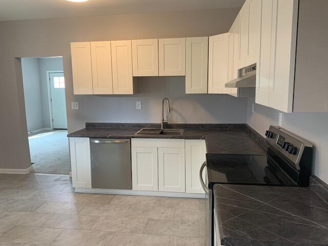 kitchen with dishwasher, range with electric cooktop, sink, light colored carpet, and white cabinetry