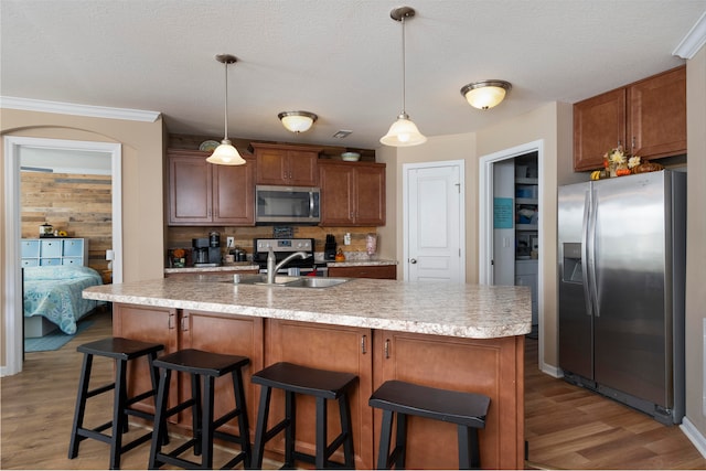 kitchen featuring dark wood-type flooring, stainless steel appliances, ornamental molding, sink, and decorative light fixtures