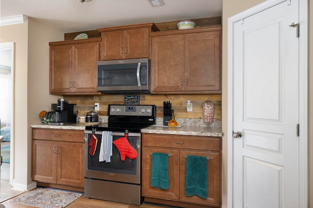 kitchen with light hardwood / wood-style flooring, stainless steel appliances, backsplash, crown molding, and a textured ceiling