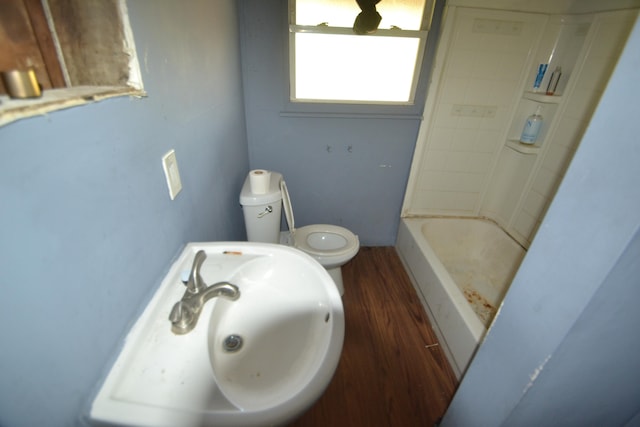 full bathroom with sink, washtub / shower combination, hardwood / wood-style flooring, and toilet