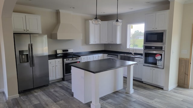 kitchen featuring white cabinets, a breakfast bar area, appliances with stainless steel finishes, a kitchen island, and custom range hood