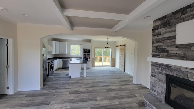 kitchen with white cabinets, a kitchen island, a barn door, light hardwood / wood-style flooring, and pendant lighting