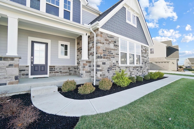 view of exterior entry with covered porch, a yard, and a garage