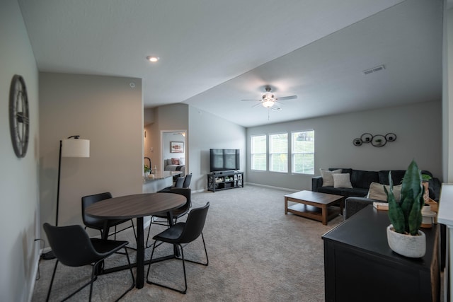 carpeted living room with ceiling fan and vaulted ceiling