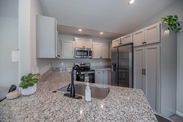 kitchen with stainless steel appliances, sink, kitchen peninsula, and light stone counters