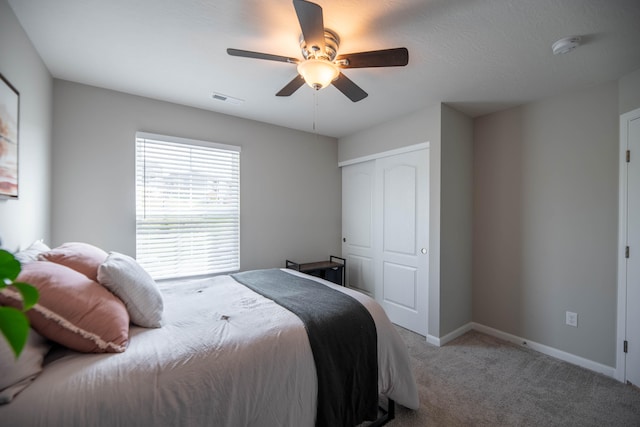 bedroom featuring light carpet, ceiling fan, and a closet