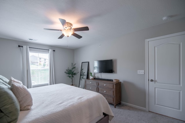 bedroom with a textured ceiling, light carpet, and ceiling fan