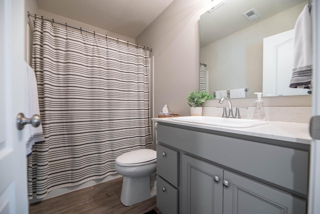 bathroom featuring a textured ceiling, vanity, hardwood / wood-style flooring, and toilet