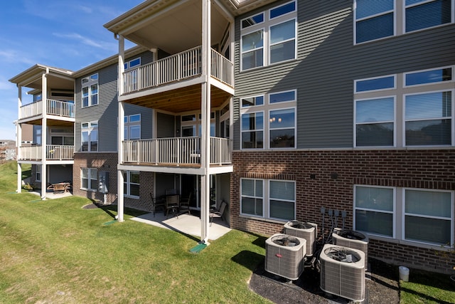 rear view of property with a patio, a yard, central AC unit, and a balcony