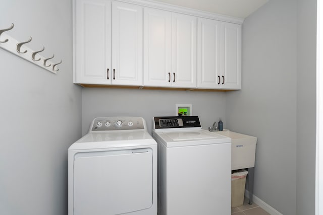 clothes washing area featuring cabinets, light tile patterned flooring, sink, and washer and clothes dryer