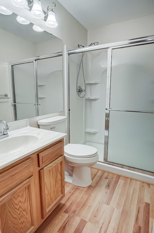 bathroom featuring walk in shower, wood-type flooring, toilet, and vanity