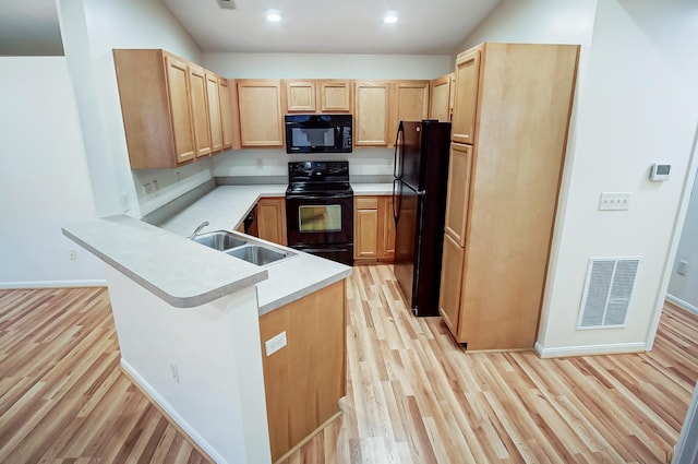 kitchen with light brown cabinetry, black appliances, sink, kitchen peninsula, and light hardwood / wood-style flooring