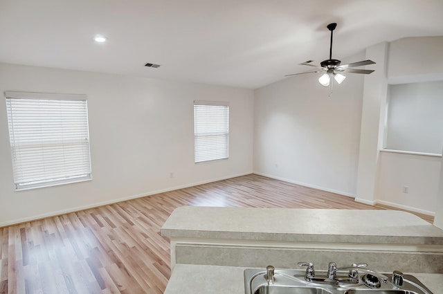 interior space with vaulted ceiling, ceiling fan, sink, and light hardwood / wood-style flooring