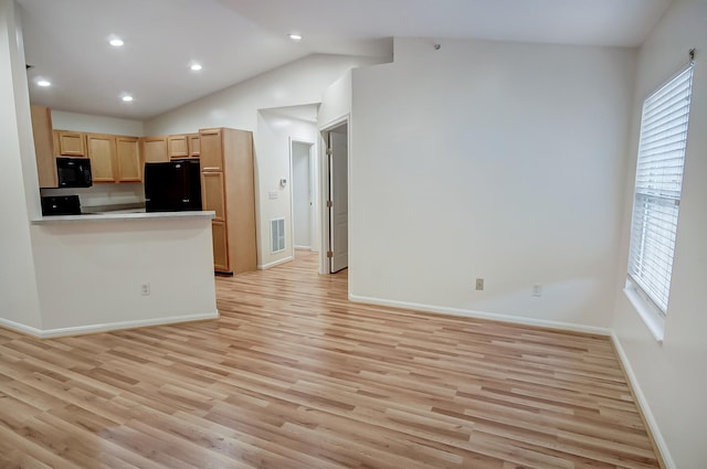 kitchen with lofted ceiling, light brown cabinets, kitchen peninsula, light hardwood / wood-style floors, and black appliances