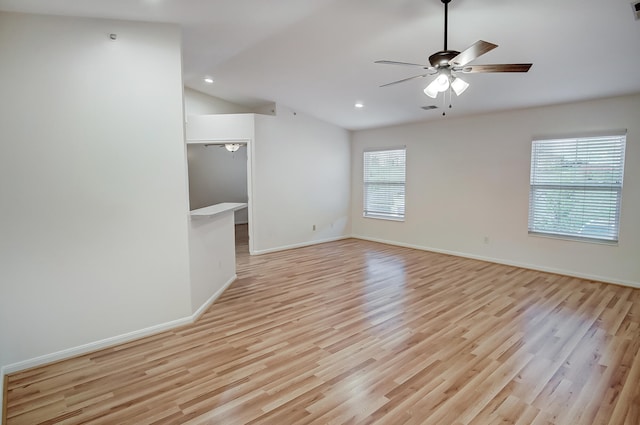 empty room with lofted ceiling, light hardwood / wood-style flooring, and ceiling fan