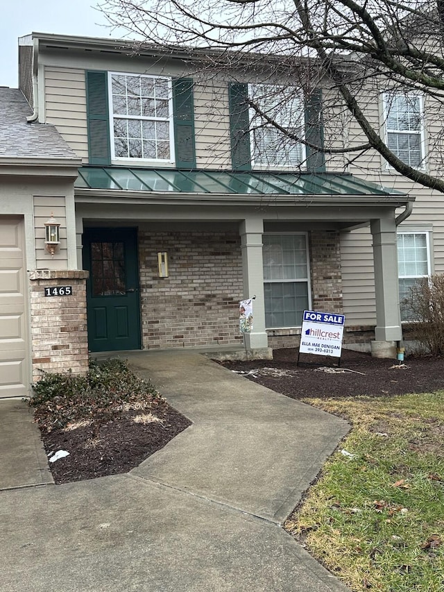 property entrance with a standing seam roof, a porch, metal roof, and brick siding