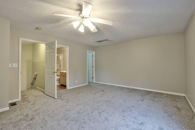 unfurnished bedroom with ensuite bath, a textured ceiling, ceiling fan, and light colored carpet