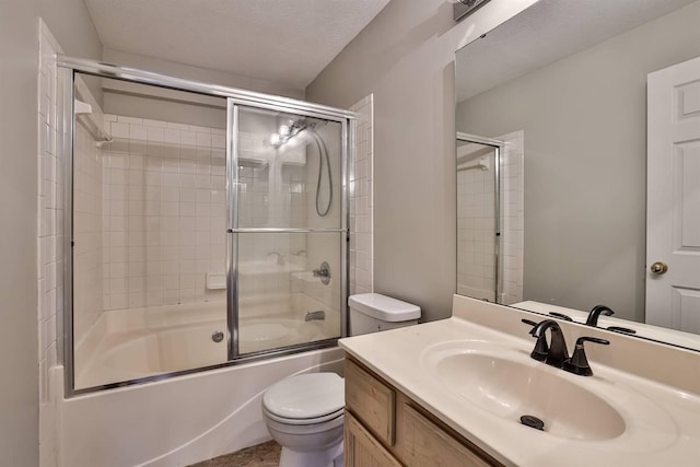 full bathroom featuring combined bath / shower with glass door, vanity, a textured ceiling, and toilet