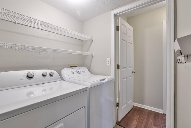 laundry room featuring washer and clothes dryer, a textured ceiling, and dark wood-type flooring