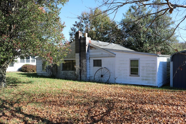 rear view of house with a storage shed and a lawn