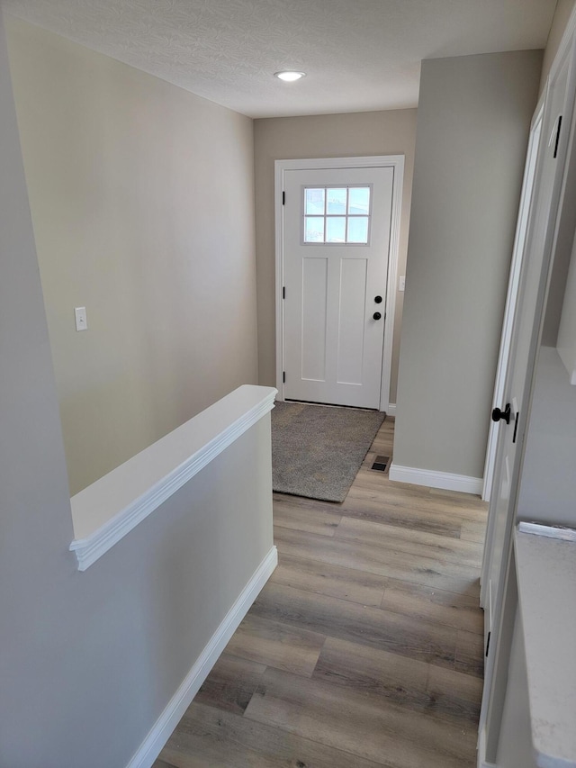 entryway with a textured ceiling and light wood-type flooring