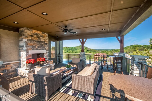 view of patio featuring a ceiling fan and an outdoor living space with a fireplace