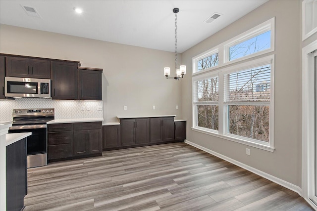 kitchen featuring visible vents, appliances with stainless steel finishes, light countertops, pendant lighting, and backsplash