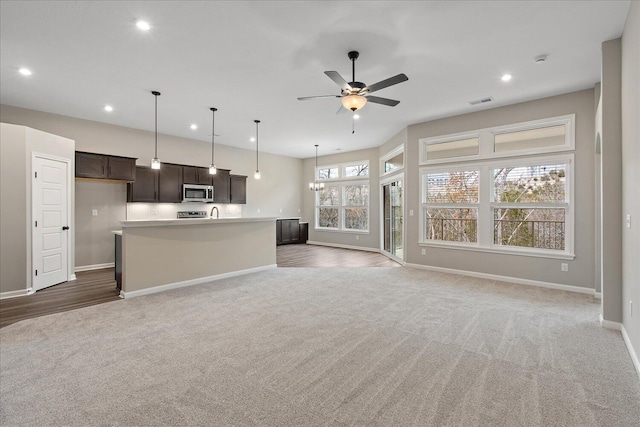 unfurnished living room featuring a ceiling fan, recessed lighting, dark carpet, and baseboards