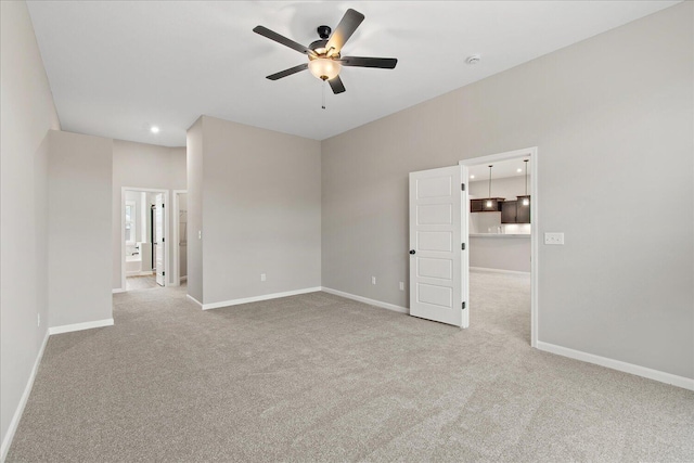 empty room featuring a ceiling fan, recessed lighting, light colored carpet, and baseboards