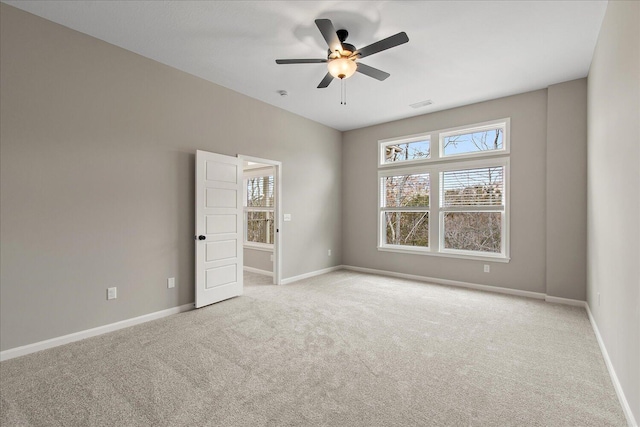 spare room with light carpet, visible vents, baseboards, and a ceiling fan