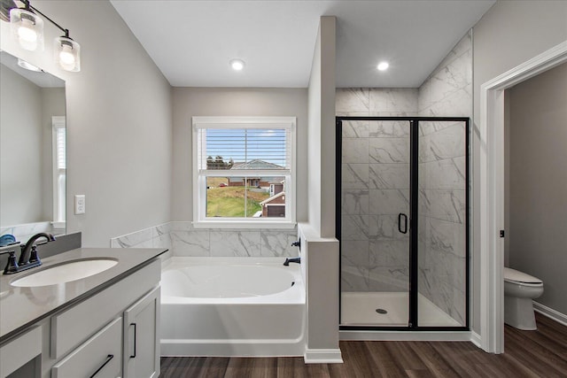 bathroom with a garden tub, toilet, vanity, a shower stall, and wood finished floors