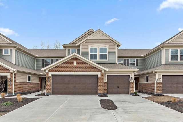 view of front of house featuring a garage, concrete driveway, brick siding, and roof with shingles