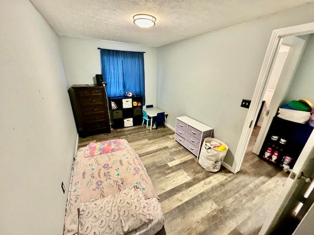 bedroom with a textured ceiling and light wood-type flooring