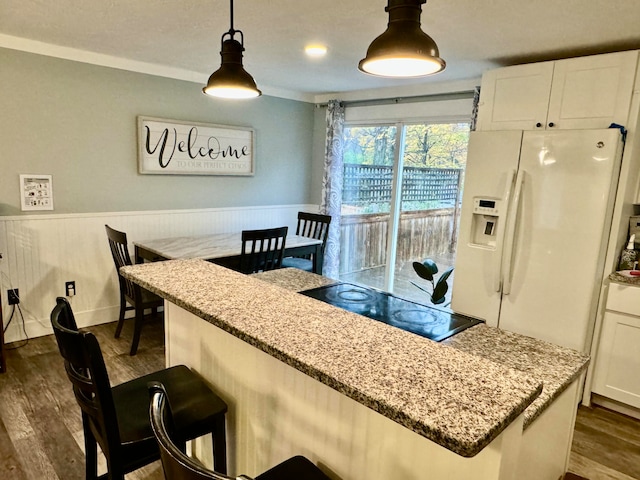 kitchen with pendant lighting, dark hardwood / wood-style floors, light stone countertops, and white cabinetry