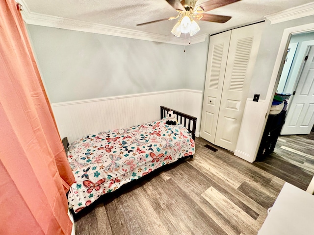 bedroom with ceiling fan, a closet, ornamental molding, and hardwood / wood-style flooring