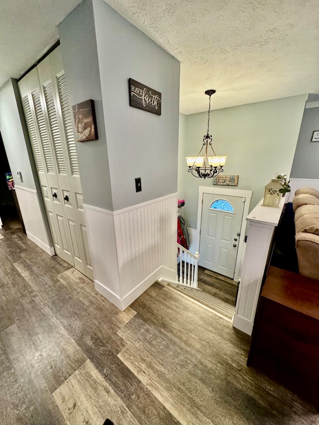 entrance foyer featuring a chandelier, a textured ceiling, and dark wood-type flooring