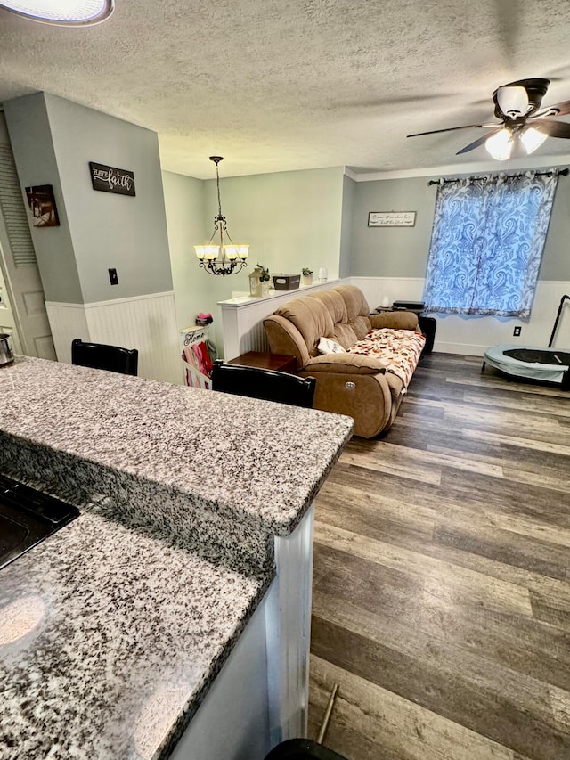 kitchen featuring hardwood / wood-style flooring, decorative light fixtures, ceiling fan with notable chandelier, and a textured ceiling