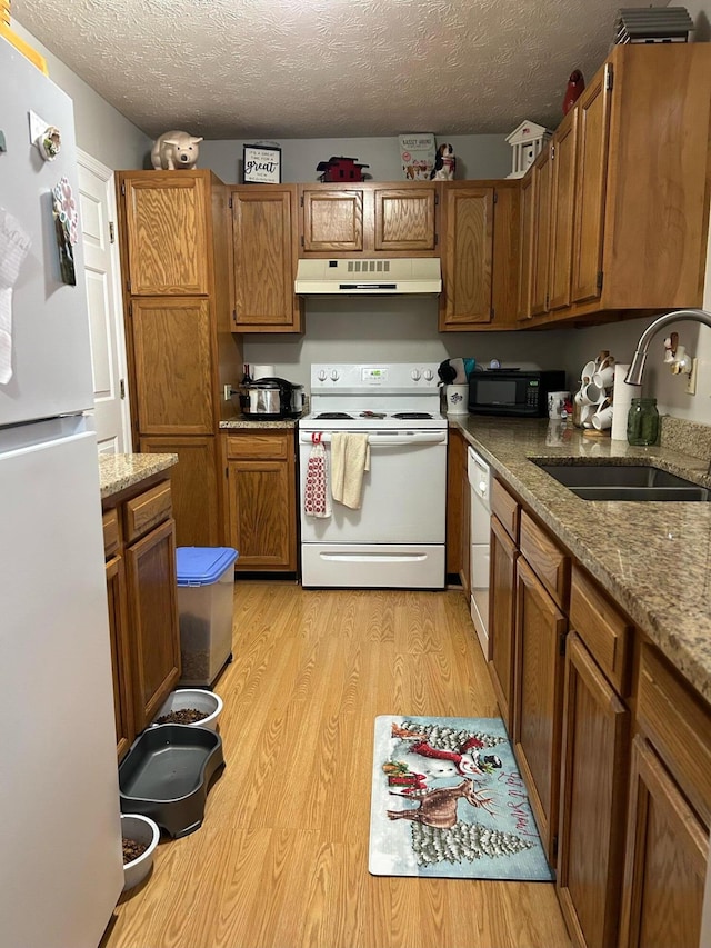 kitchen with light stone counters, light wood-type flooring, a textured ceiling, sink, and white appliances