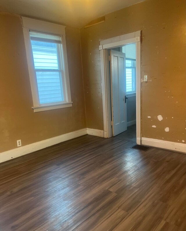 spare room with a wealth of natural light and dark hardwood / wood-style floors