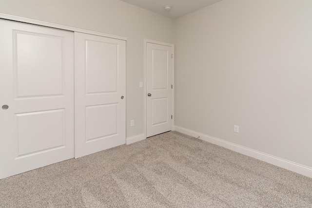 unfurnished bedroom featuring light carpet and a closet