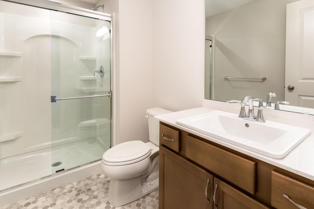 bathroom featuring toilet, vanity, and an enclosed shower