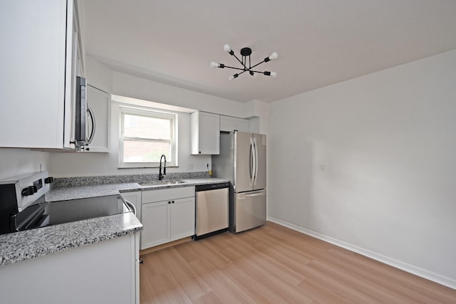 kitchen with stainless steel appliances, sink, light stone countertops, white cabinets, and light wood-type flooring