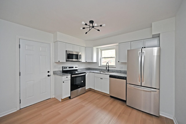 kitchen with stainless steel appliances, white cabinets, sink, and light wood-type flooring