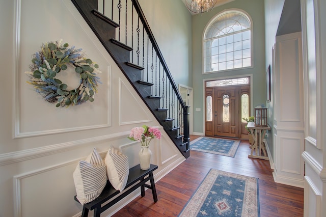 foyer with a notable chandelier, a towering ceiling, and dark hardwood / wood-style floors