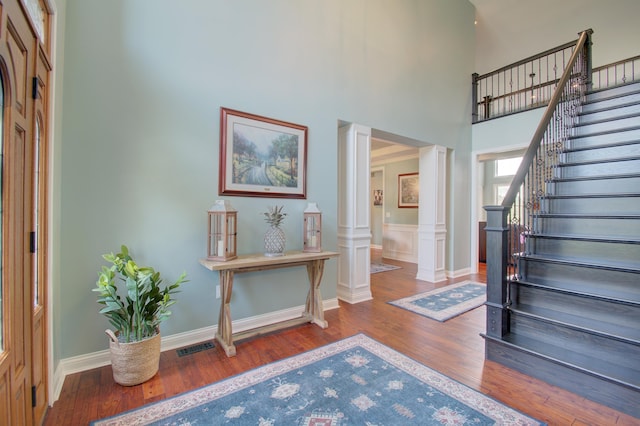 entrance foyer with decorative columns, a high ceiling, and dark hardwood / wood-style flooring