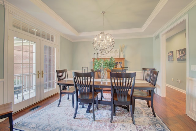 dining room with french doors, a chandelier, ornamental molding, a tray ceiling, and hardwood / wood-style floors