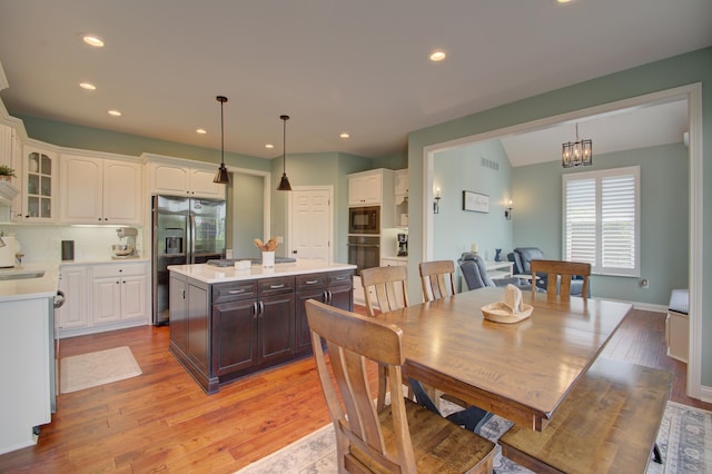 dining area featuring sink, an inviting chandelier, and light hardwood / wood-style floors