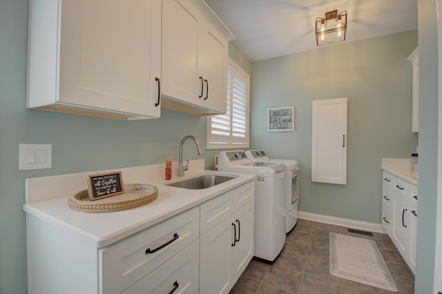 clothes washing area with sink, tile patterned floors, cabinets, and washing machine and clothes dryer