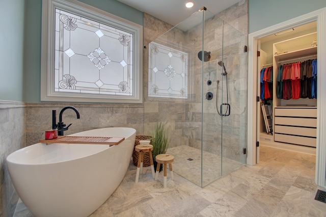 bathroom featuring plus walk in shower and tile walls